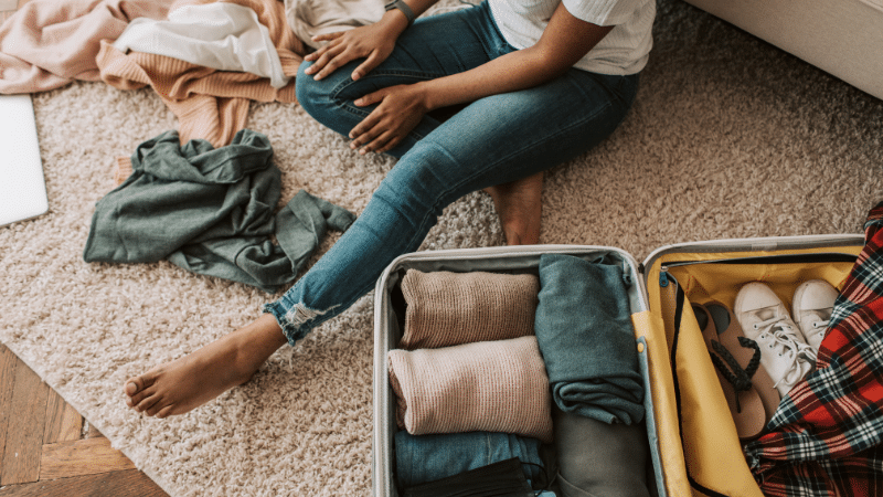 woman packs a suitcase on the floor in preparation for her vacation