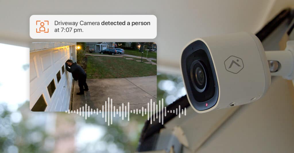 a man suspiciously looks into a garage while a video monitoring system detects the activity and sends a message "driveway camera detected a person at 7:07pm" 