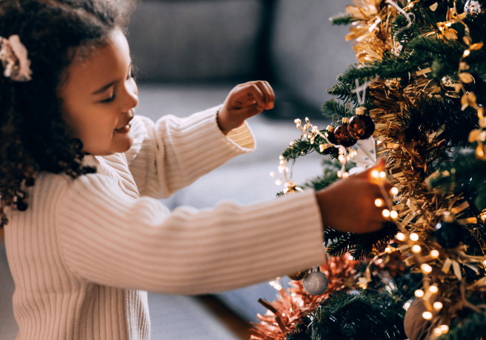 girl decorates christmas tree with lighting